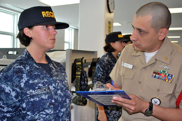 A Navy female recruit is inspected to ensure she meets the grooming and uniform standards