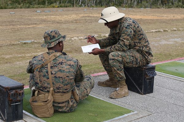 Range coach gives a Marine advice about their shot grouping to prepare for USMC rifle qualification 