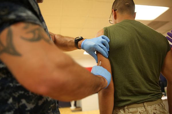Petty Officer gives a vaccination to a recruit
