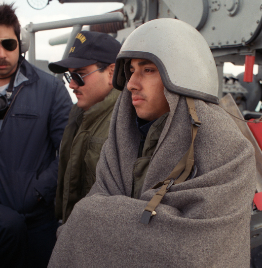 navy sailor wears his woobie blanket while standing watch