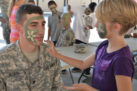 a soldier gets his face painted by a military pen pal